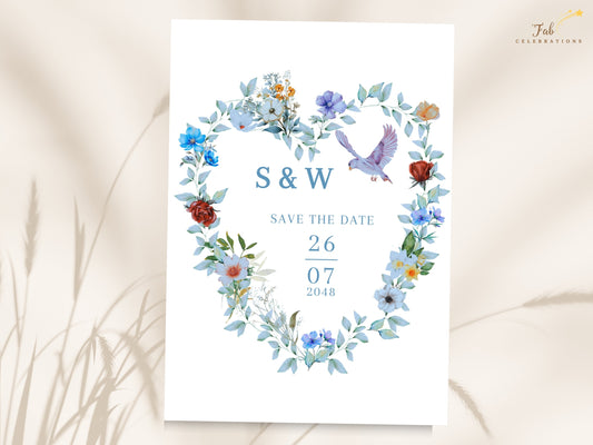 Blue and Green Save the Date Card featuring a watercolor-inspired heart-shaped wreath with blue flowers, green foliage and two graceful doves framing the couple's initials and wedding date.