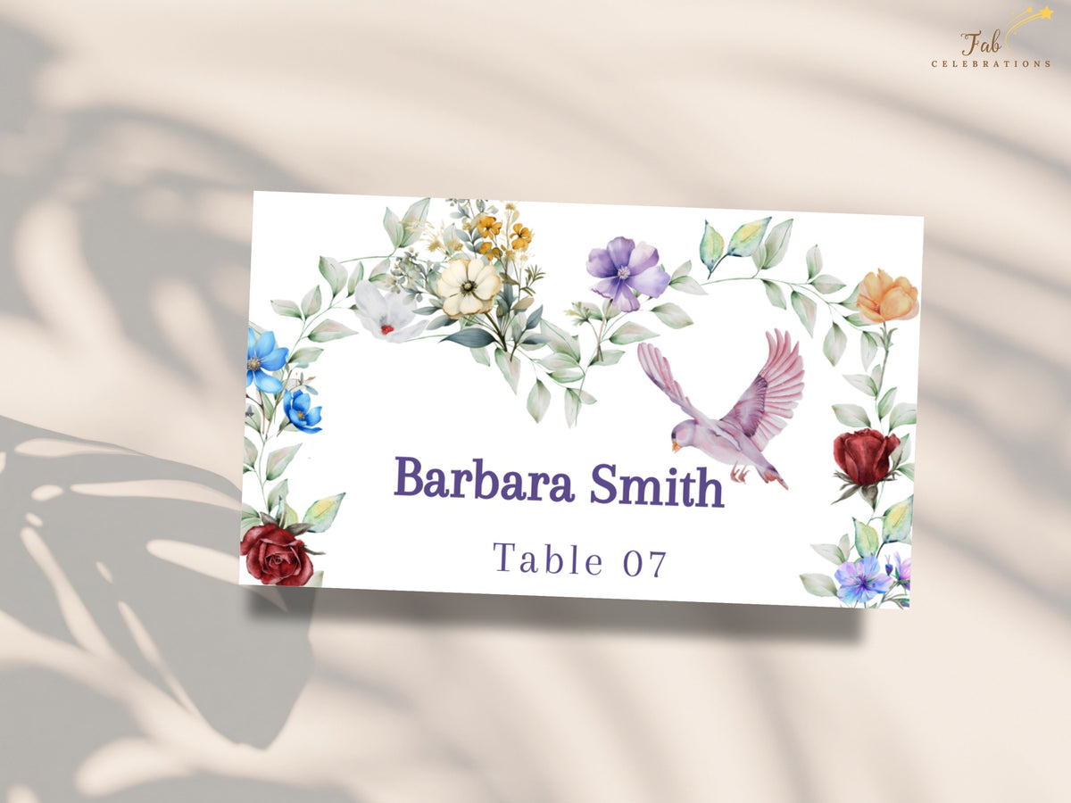 Floral reception place card featuring watercolor-inspired colorful blossoms, soft leafy greenery and a graceful dove surrounding the guest name Barbara Smith and table number 07.