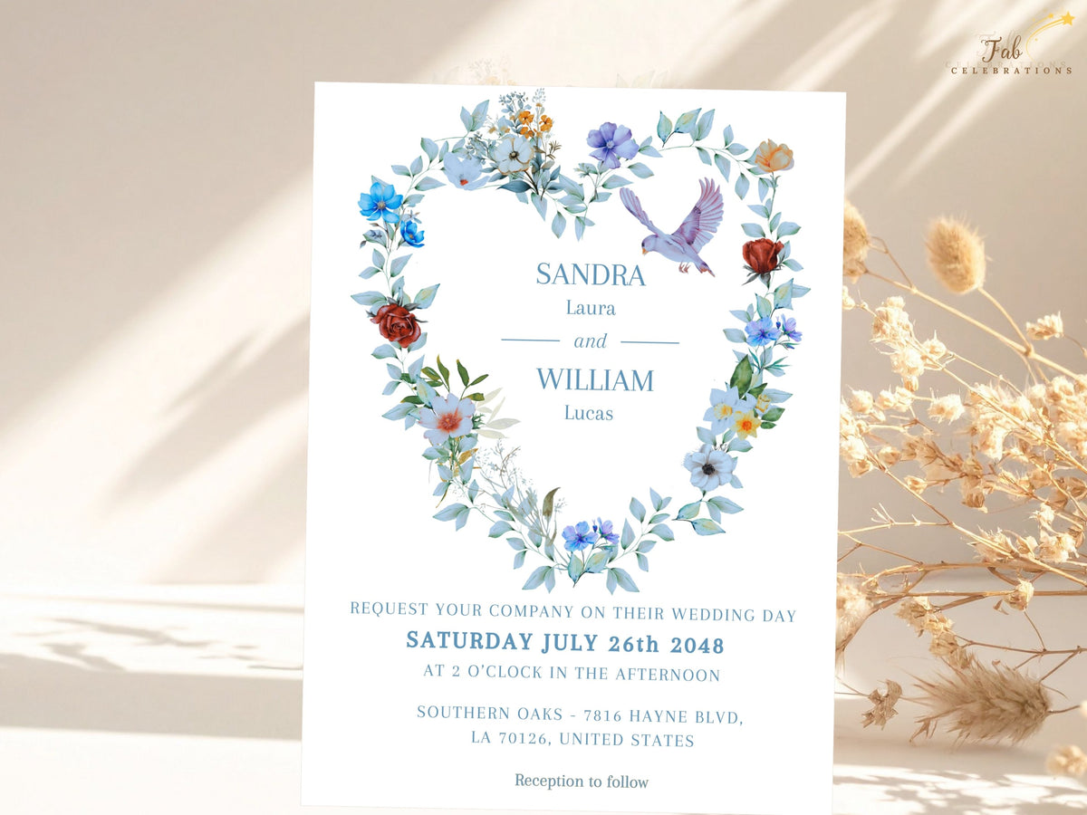 Wedding invitation front with a watercolor-inspired floral dove design, featuring dusty blue blooms, ivory accents and airy greenery arranged as a heart wreath around elegant wedding typography.