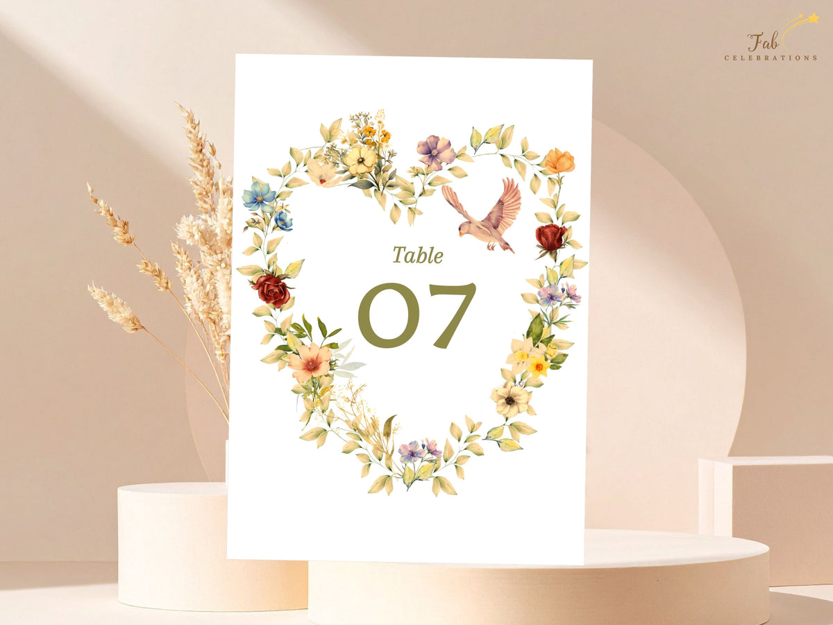Elegant wedding table number design with a watercolor-inspired heart of golden and blush flowers, sage greenery, and two doves framing the editable table number for a coordinated reception.