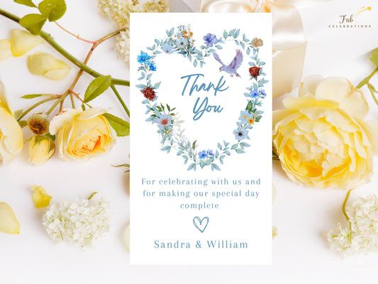 Elegant Wedding Thank You Card featuring a watercolor-inspired heart-shaped wreath with blue flowers, green foliage, delicate butterflies and a graceful dove surrounding a handwritten-style Thank You message.