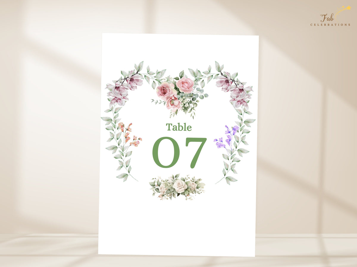 Wedding table number featuring Table 07 framed by a watercolor-inspired heart wreath of pink roses, purple blossoms, greenery and delicate floral details for reception tables.