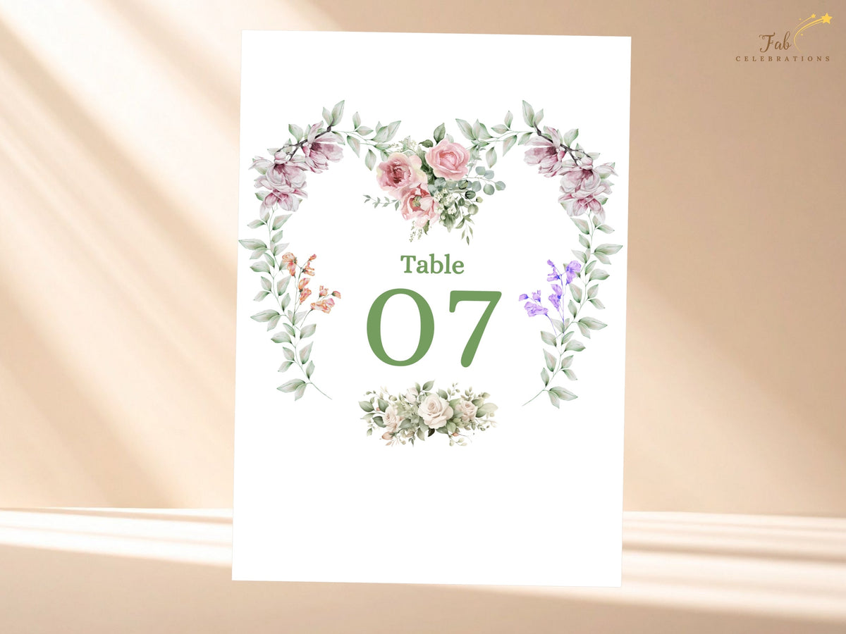 Wedding table number card featuring Table 07 surrounded by watercolor-inspired pink roses, purple blossoms and soft green foliage arranged in an elegant heart-shaped floral design.