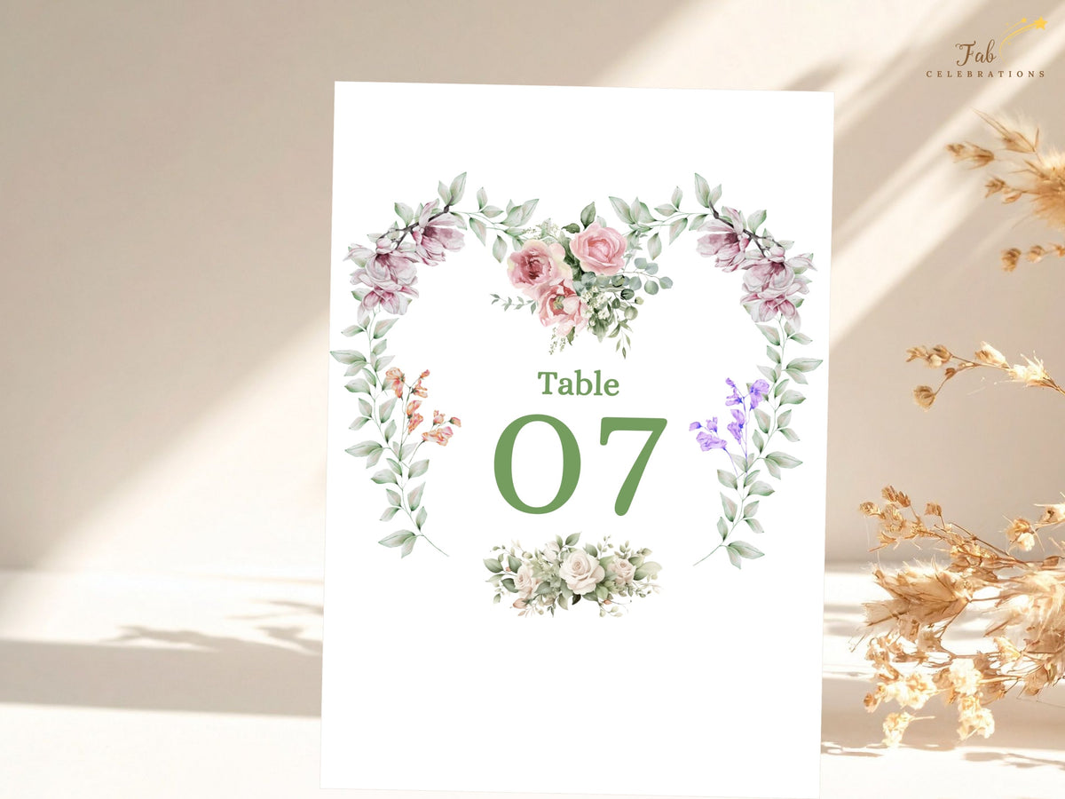 Romantic reception table card featuring Table 07 surrounded by watercolor-inspired pink roses, purple blossoms and greenery in a delicate heart-shaped floral arrangement.