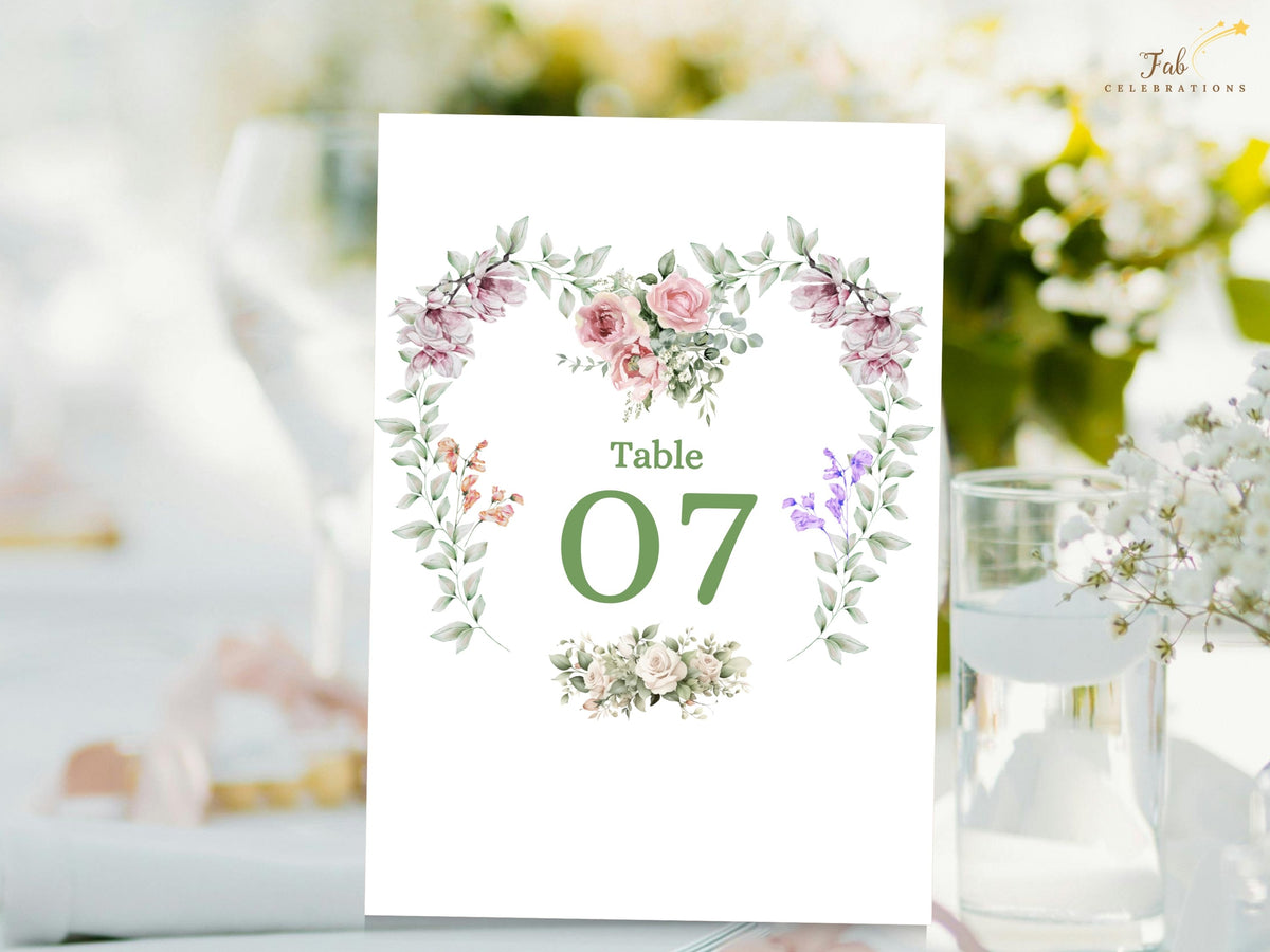 Romantic wedding table number card featuring Table 07 surrounded by a watercolor-inspired heart wreath of pink roses, purple blossoms and delicate green botanical accents.