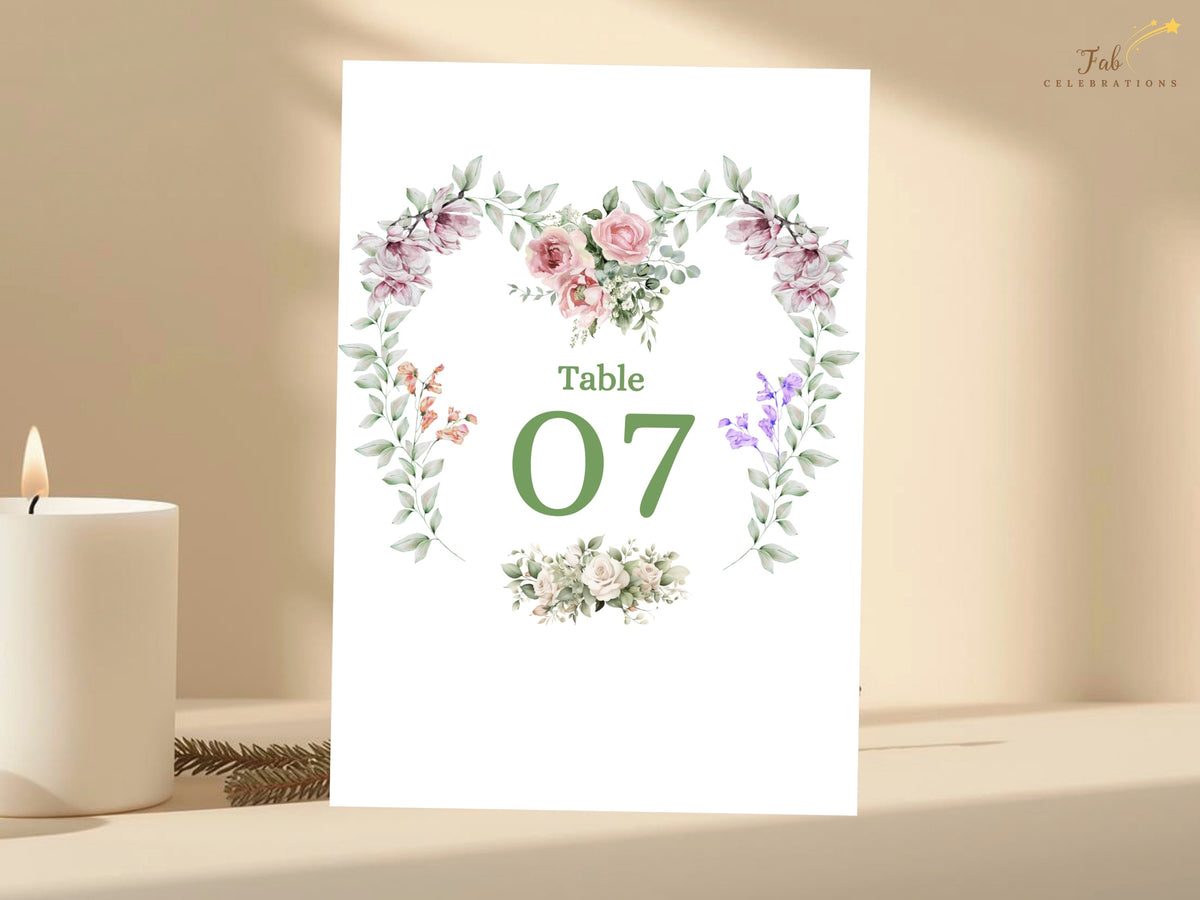 Wedding table card featuring Table 07 inside a romantic watercolor-inspired floral heart wreath with pink roses, purple flowers and soft greenery for coordinated reception decor.