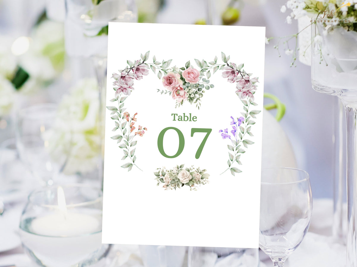 Wedding table number card featuring Table 07 framed by a watercolor-inspired floral heart wreath with pink roses, purple blossoms, greenery and delicate botanical accents.