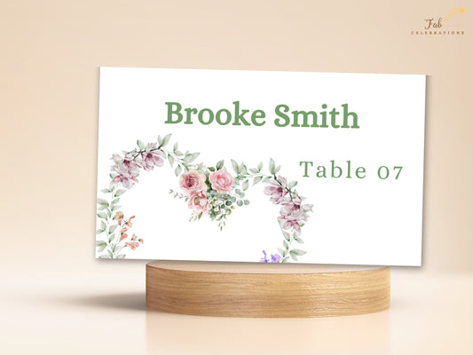Ivory Wedding Invitations place card featuring the guest name Brooke Smith and Table 07 with watercolor-inspired pink roses, purple blossoms and greenery in a delicate floral arrangement.