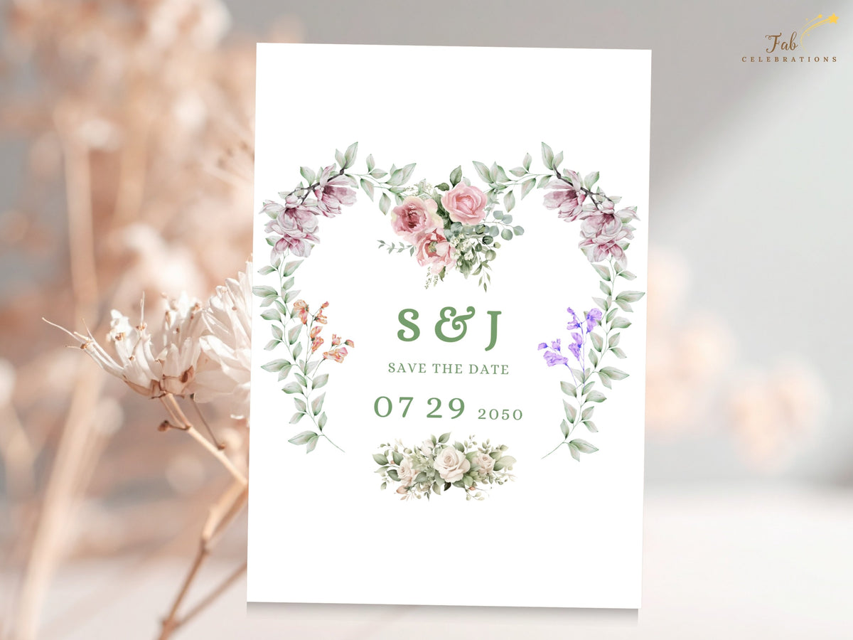 Romantic save the date card featuring couple initials and wedding date inside a watercolor-inspired heart wreath of pink roses, purple blossoms and delicate green botanical accents.
