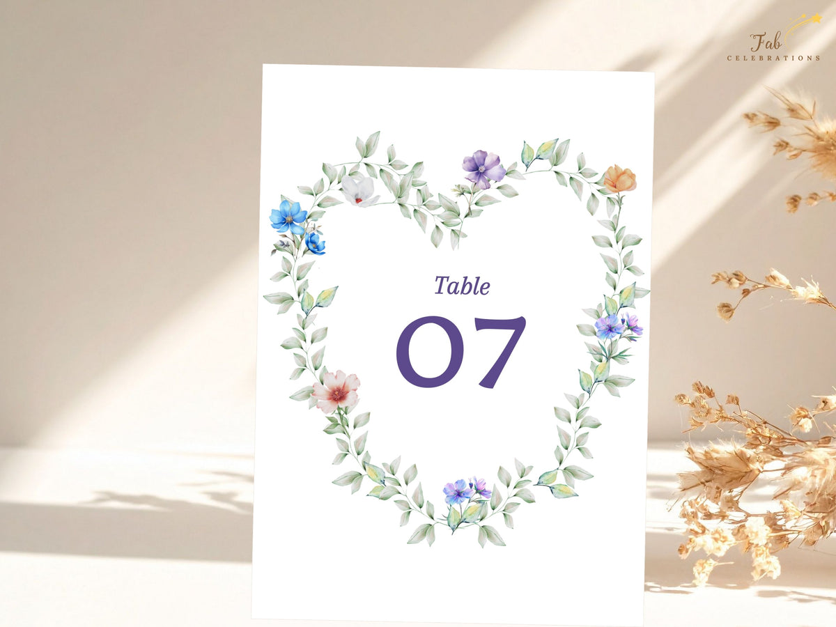Pastel Garden Table Number featuring an elegant purple number centered within a watercolor-inspired floral wreath of airy green foliage and delicate pastel flowers for wedding reception tables.