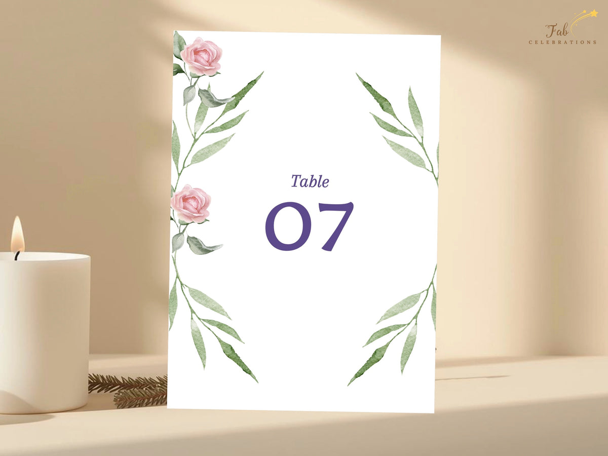 Wedding table number card featuring watercolor-inspired pink roses and elegant green foliage framing a prominent purple number for a cohesive floral reception stationery design.