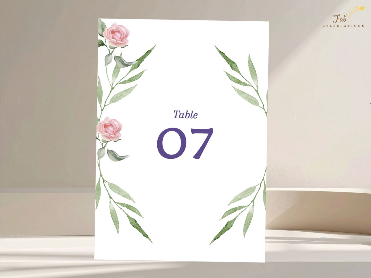 Refined wedding table number card decorated with watercolor-inspired blush pink roses and graceful green foliage, with a large purple table number centered in a clean layout.