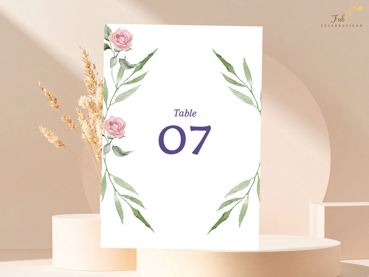 Wedding table number card with watercolor-inspired blush roses and delicate green foliage, presenting a bold purple table number in a clean and softly romantic botanical layout.