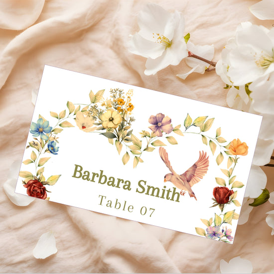 Video showcasing the Romantic Wedding Name Card featuring a watercolor-inspired half floral heart wreath, graceful dove illustration, soft beige background and editable Canva template for elegant wedding place settings.