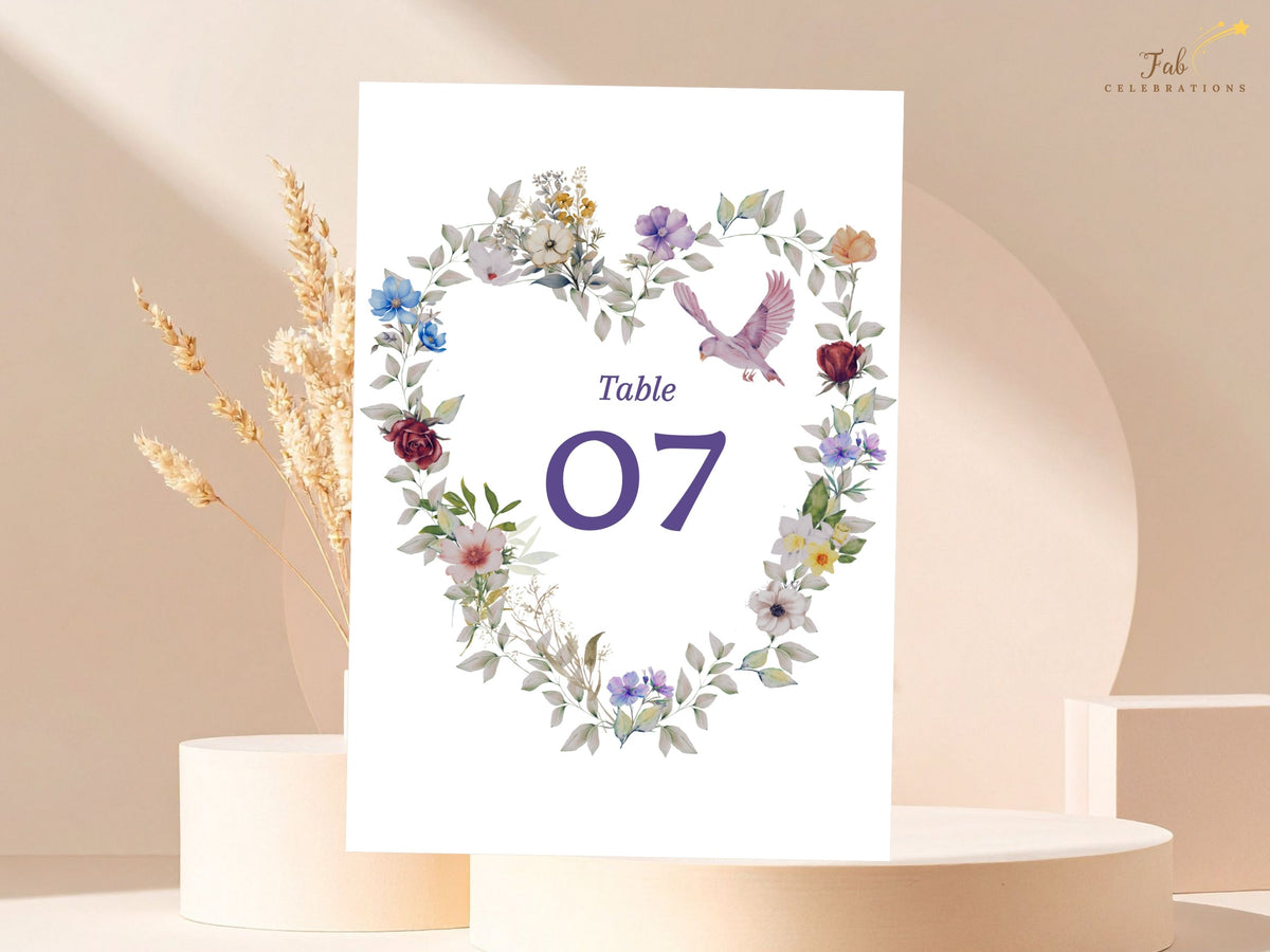 Romantic wedding table number seven surrounded by a watercolor-inspired floral heart, fine greenery and a pale pink dove, ready for personalization in Canva. Editable in Canva. Matching stationery.