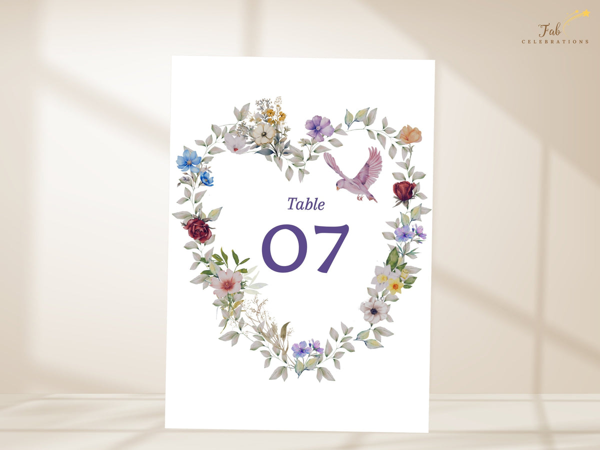 Wedding table number seven template decorated with a watercolor-inspired heart wreath of purple, blue and rose blooms, botanical leaves and a graceful dove. Editable in Canva. Matching stationery.