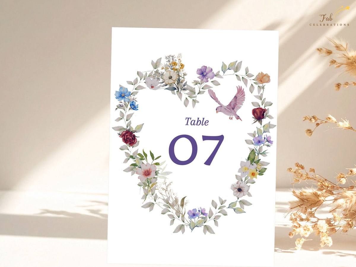 Romantic table number seven card featuring a watercolor-inspired floral heart in blue, purple and blush tones, finished with a delicate dove and editable lettering. Editable in Canva.