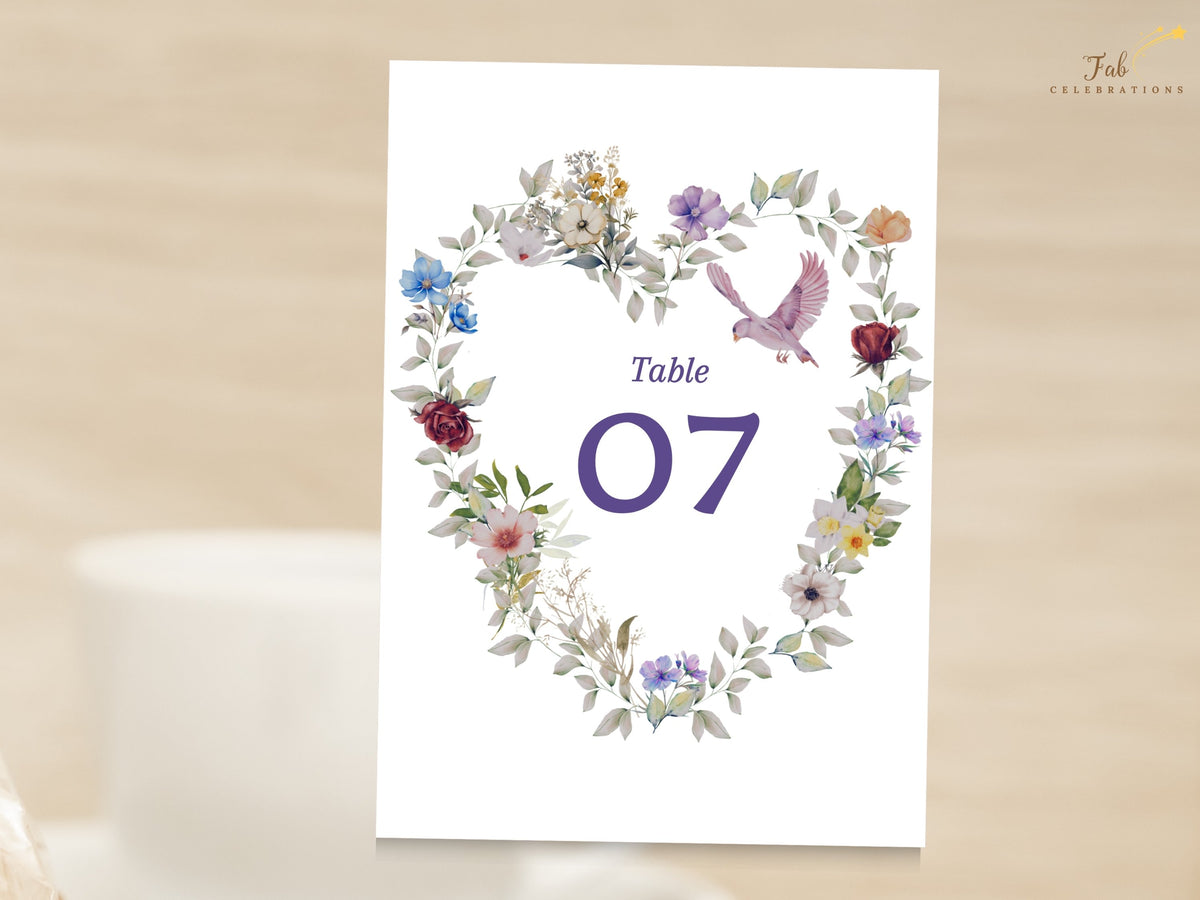 Editable purple floral wedding table number with watercolor-inspired blossoms forming a delicate heart, a pale pink dove and clear number seven for guest tables. Editable in Canva.