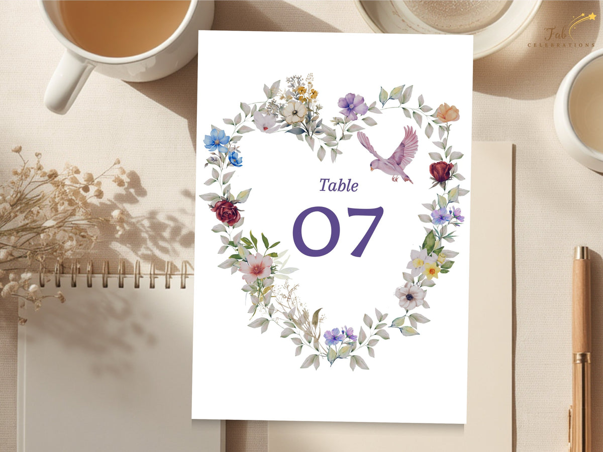 Purple floral table number template with an elegant number seven and a watercolor-inspired wreath of blue, lilac, blush and burgundy flowers surrounding the design. Editable in Canva.