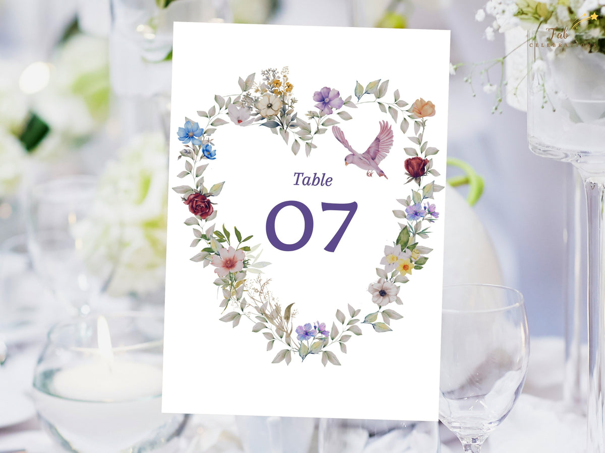 Editable table number seven card with a watercolor-inspired floral wreath, gentle purple lettering, pastel blooms and botanical accents for a romantic wedding reception. Editable in Canva.