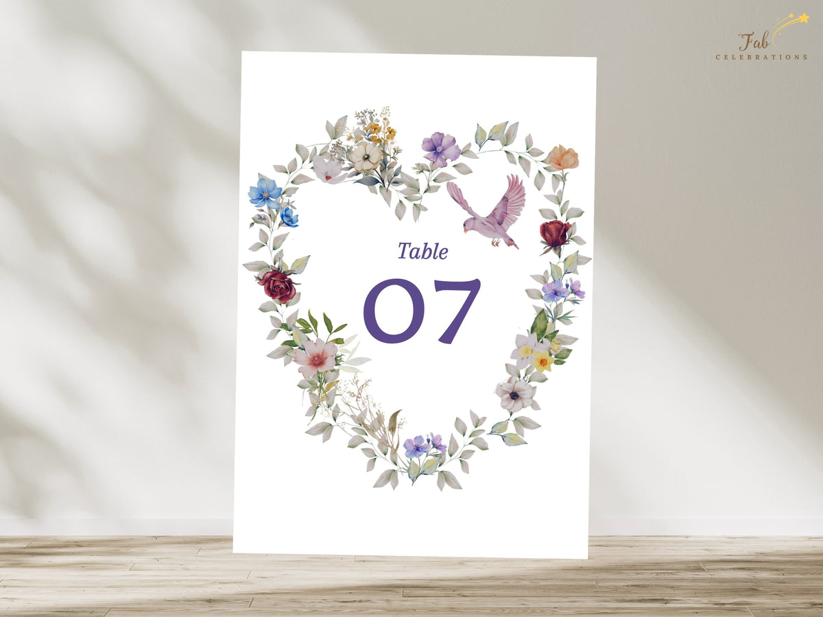 Purple floral wedding table number seven with watercolor-inspired heart-shaped flowers, lavender and blue accents, gentle foliage and a dove for romantic table styling. Editable in Canva.