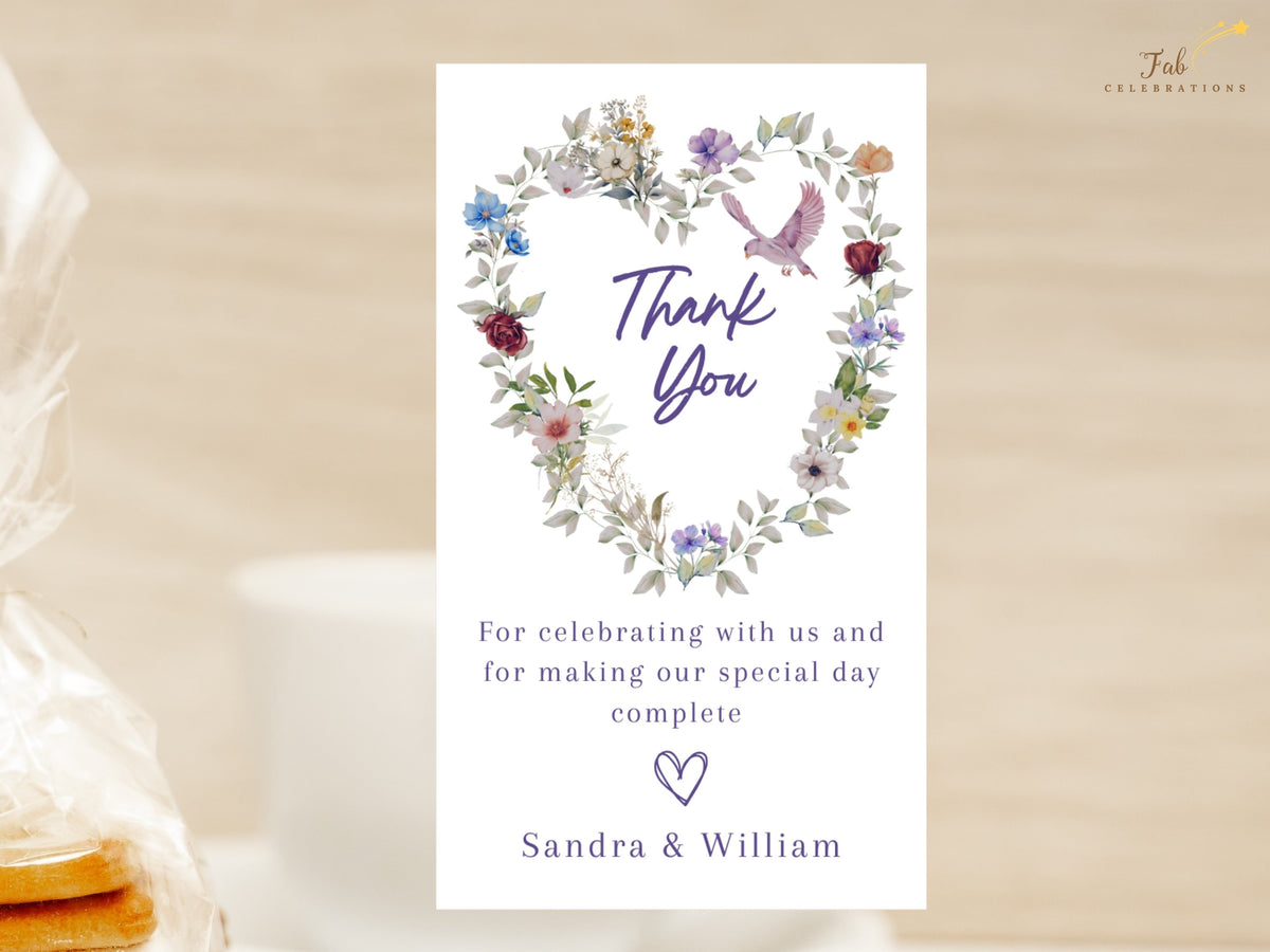 Wedding thank you template featuring watercolor-inspired botanical florals forming a delicate heart, with purple Thank You lettering, a pink dove and a personal message from the newlyweds.