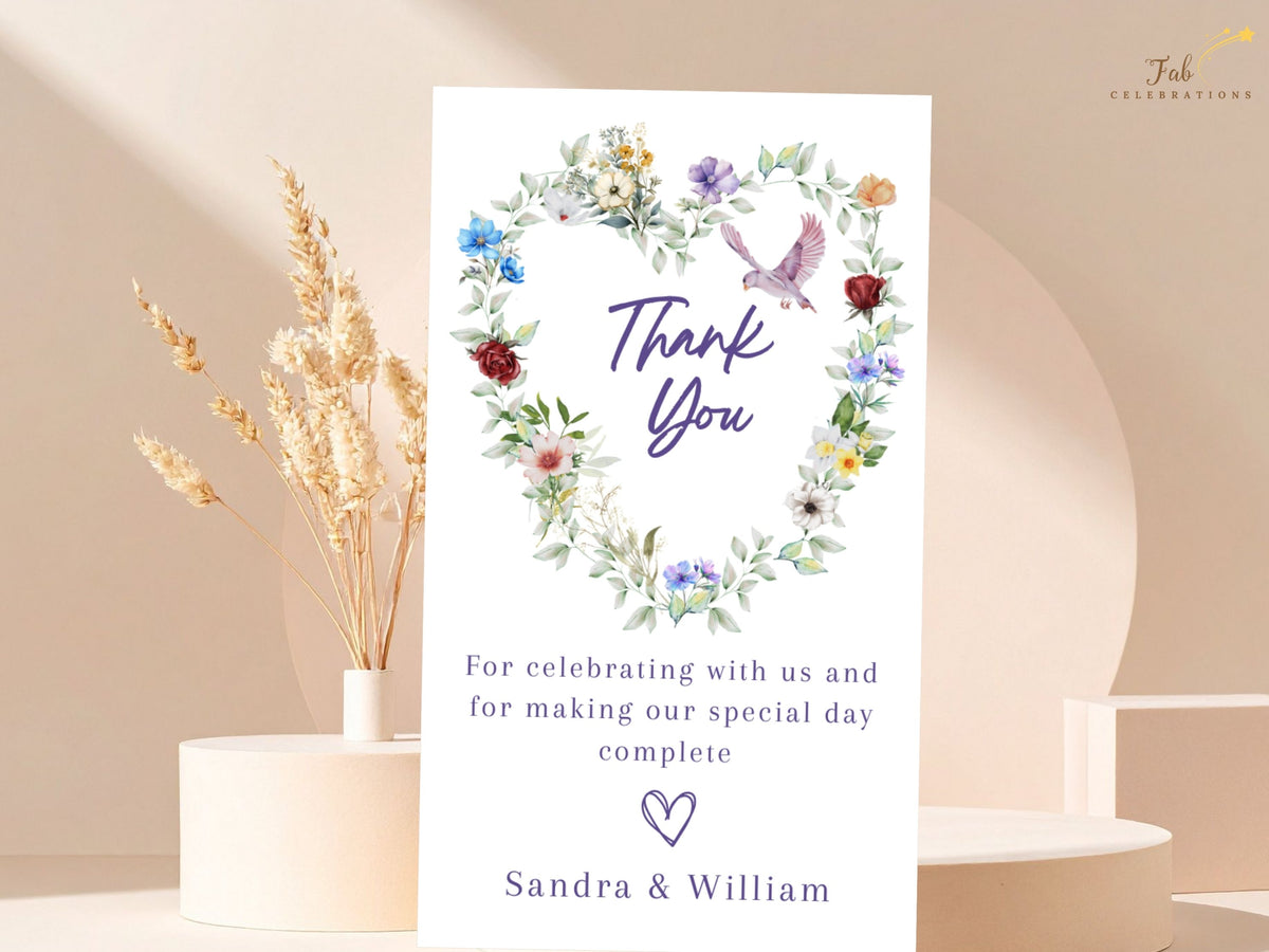 Elegant wedding thank you card featuring a watercolor-inspired heart of delicate multicolored flowers, soft greenery and a graceful dove above a warm message of gratitude from the couple.