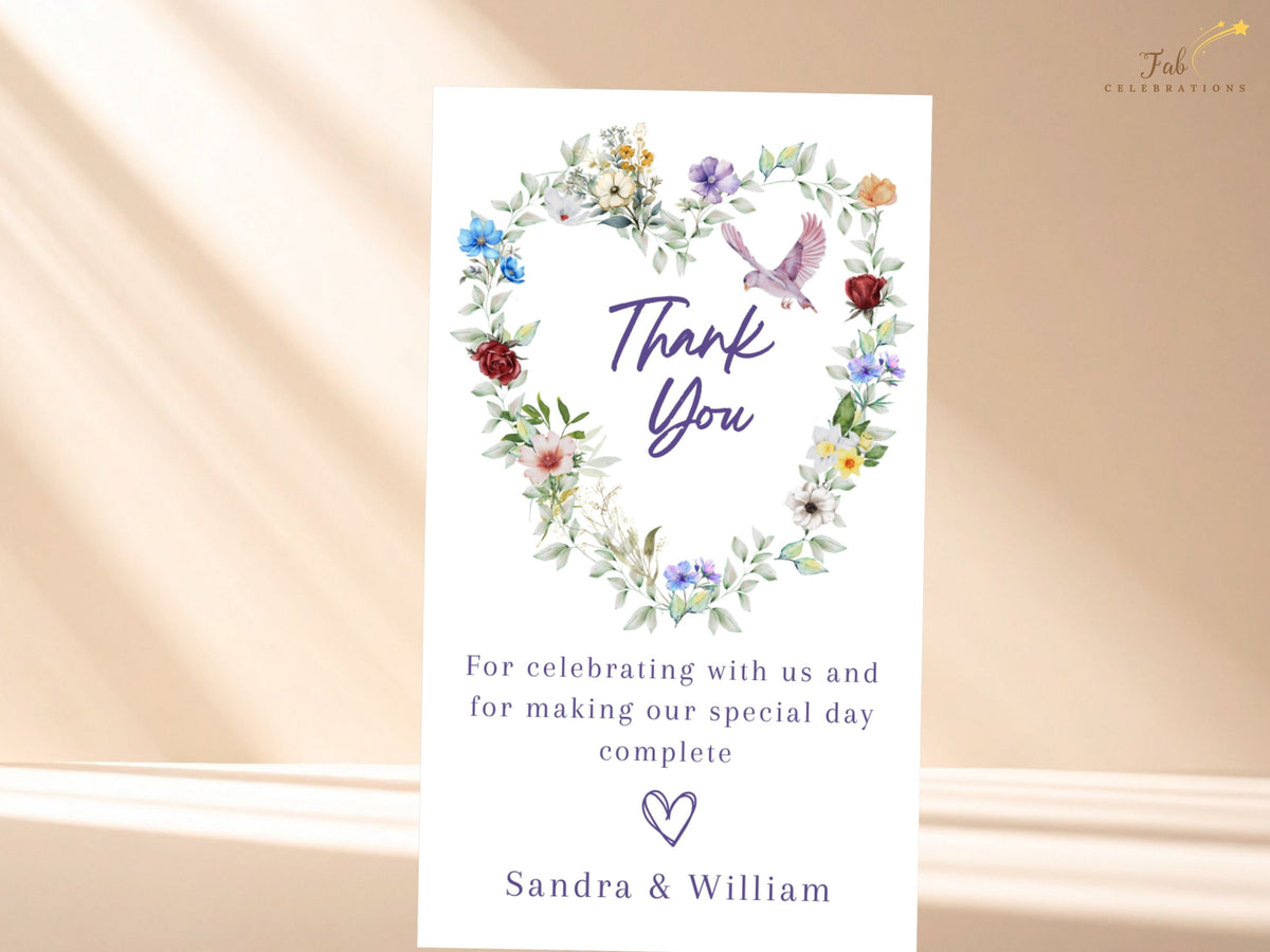 Elegant wedding thank you card featuring a watercolor-inspired floral heart of multicolored blossoms and soft greenery with a graceful dove above a warm message of appreciation from the couple.