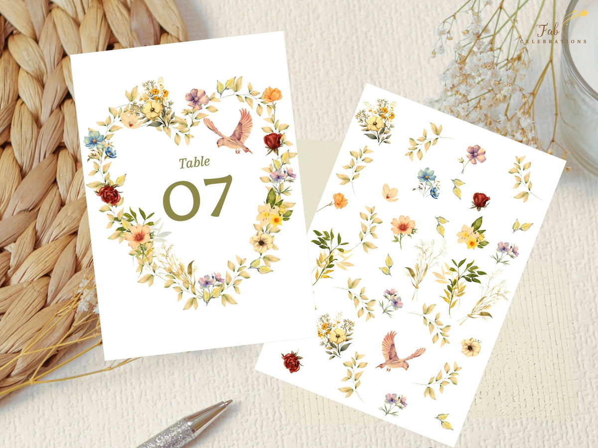 Romantic wedding table number alongside a botanical artwork sheet of matching flowers, leaves, and doves, highlighting the watercolor-inspired floral heart elements used in the design.