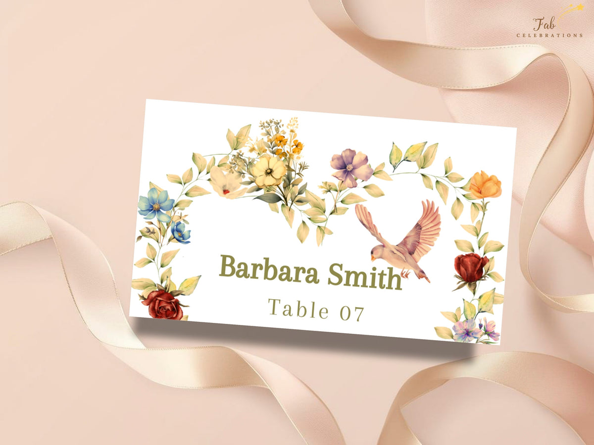 Romantic wedding place card presented with a soft blush ribbon, featuring a personalized guest name, Table 07, and delicate watercolor-inspired flowers in warm gold, ivory, and rose tones.