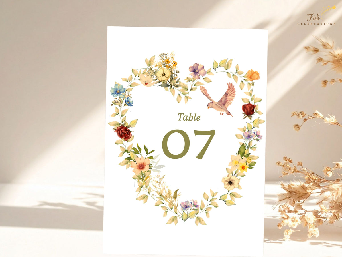 Romantic wedding table number Canva design with a floral heart of golden and blush flowers, two doves, sage foliage, and editable olive green table numbering for a timeless reception.