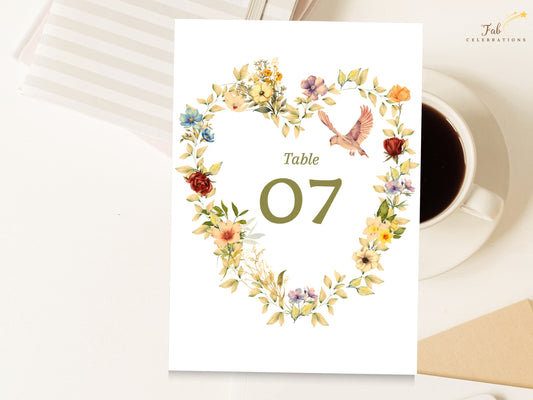 Romantic wedding table number with a watercolor-inspired floral heart wreath, two delicate doves, golden blossoms, soft blush flowers, sage leaves, and an editable table 07 centerpiece.