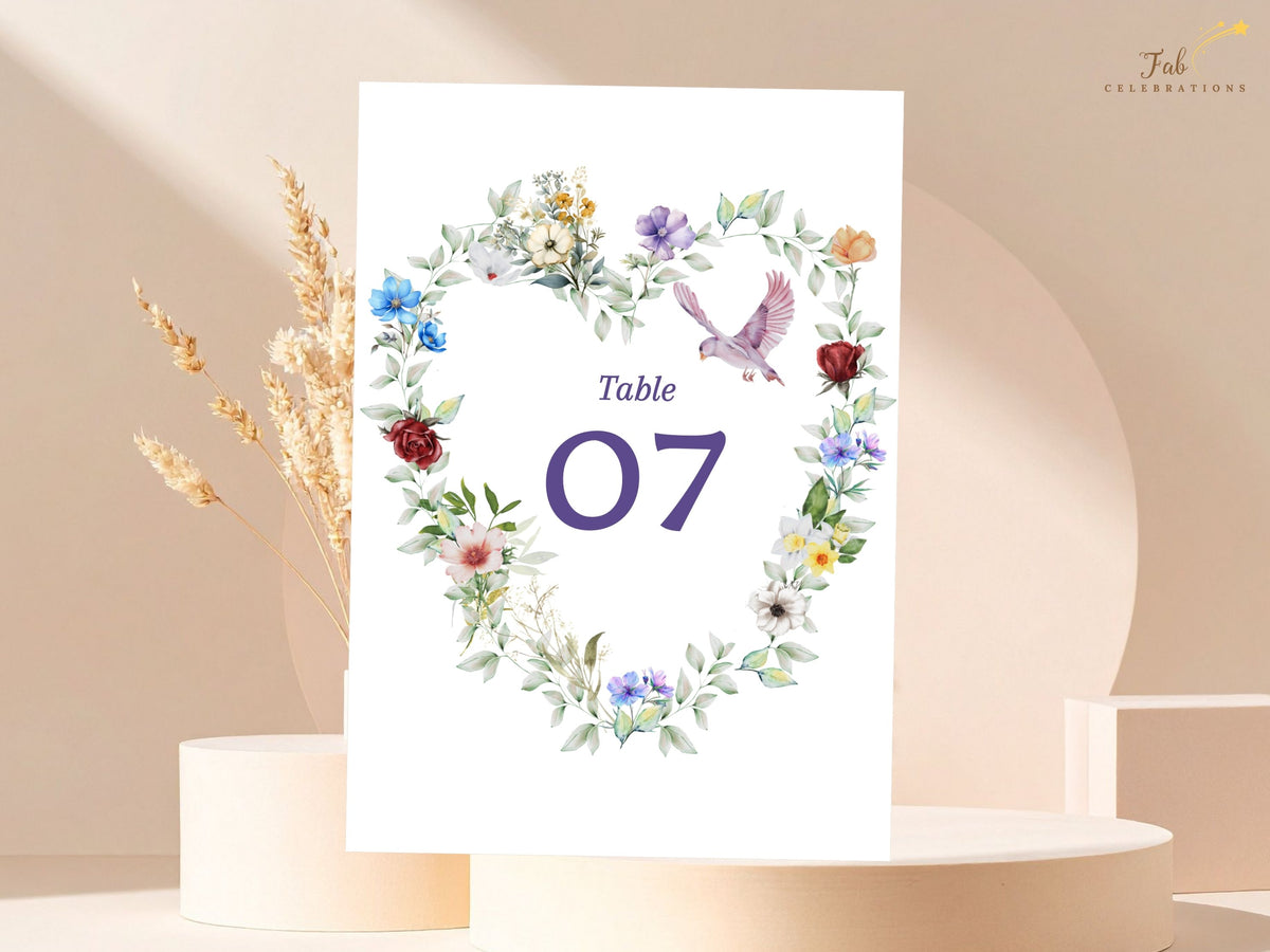 Table number card featuring a graceful dove within a watercolor-inspired heart of colorful flowers and delicate leafy greenery, framing the elegant reception table number 07.