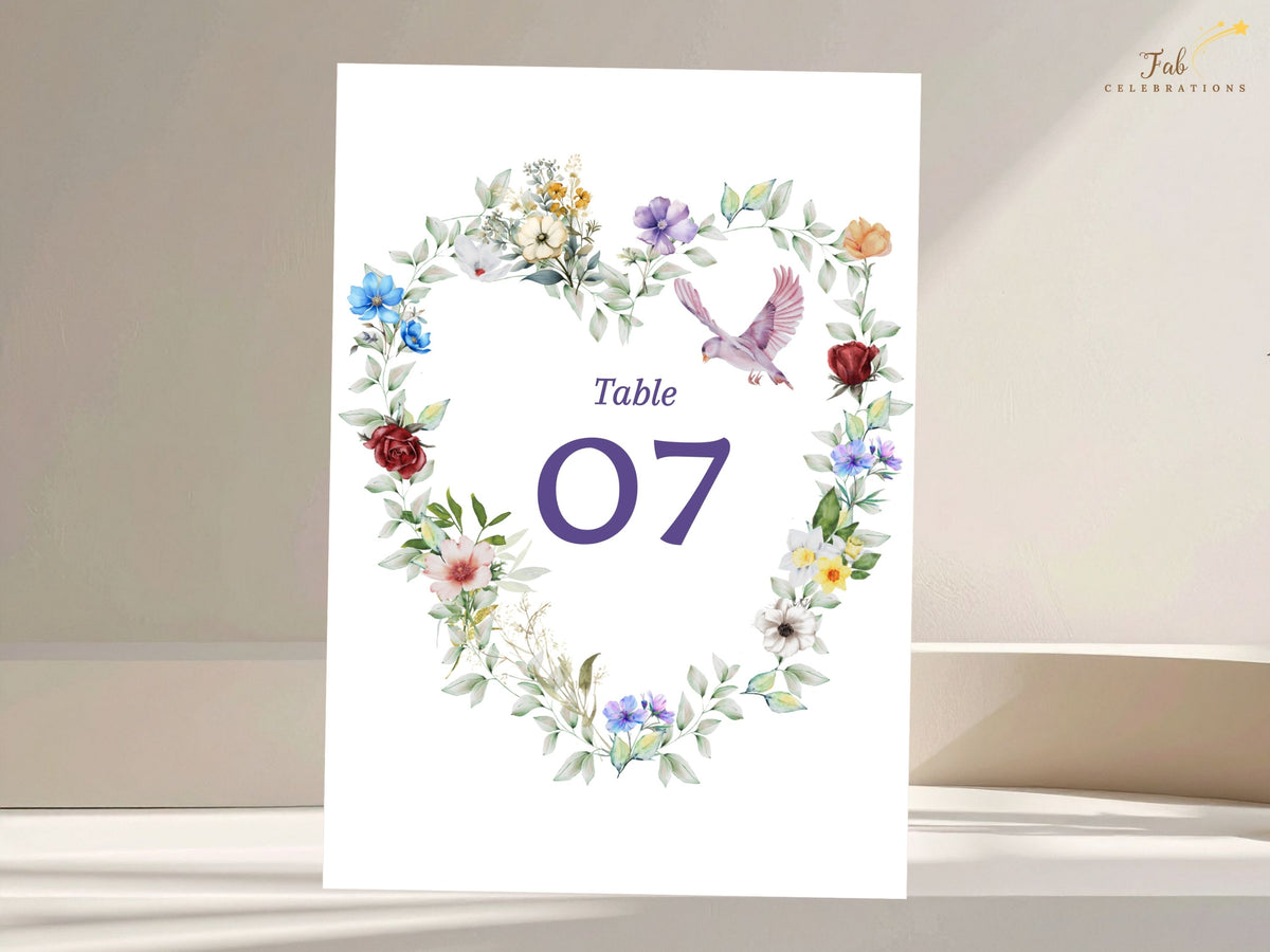 Elegant wedding table number card featuring a watercolor-inspired floral heart, colorful garden blossoms, delicate greenery and a graceful dove framing the reception number 07.