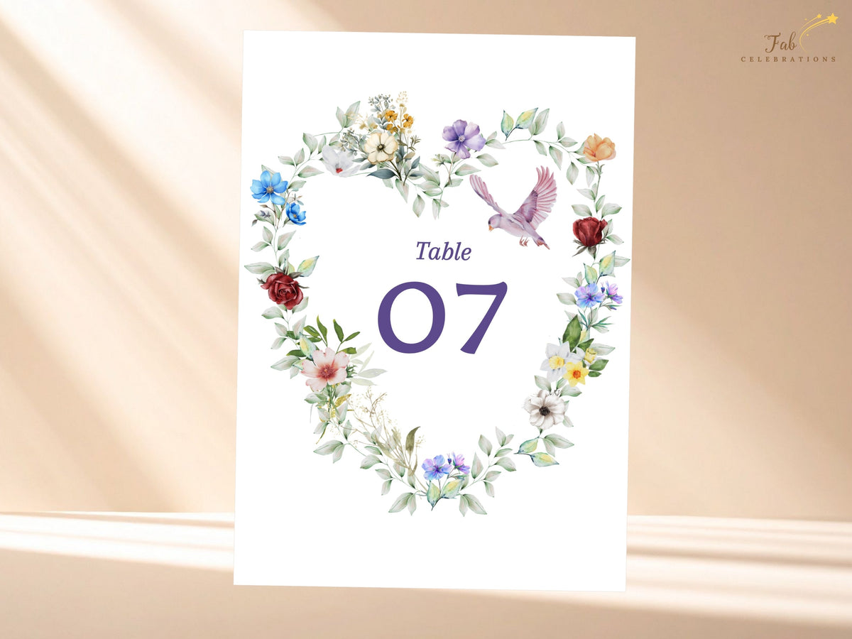 Reception table number card featuring a watercolor-inspired floral heart with delicate multicolored blossoms, leafy greenery and a graceful dove surrounding the elegant table number 07.