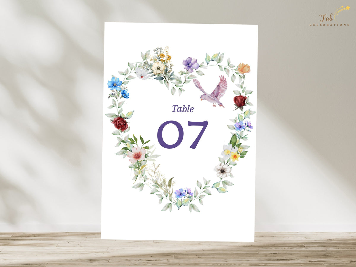 Romantic reception table number card featuring a watercolor-inspired floral heart with multicolored blossoms, leafy greenery and a graceful dove framing the elegant number 07.
