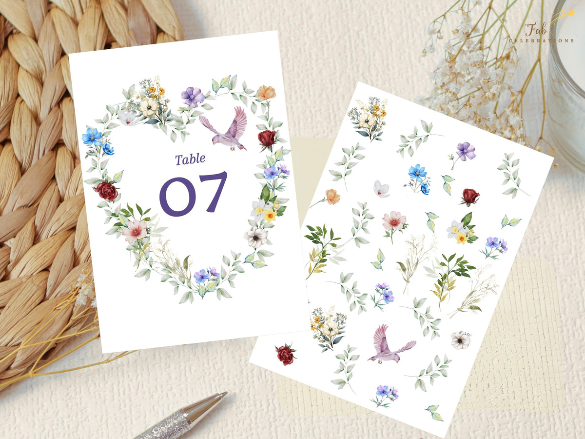 Wedding table number card displayed beside the watercolor-inspired floral elements used in the collection, including colorful blossoms, leafy greenery and graceful dove illustrations.