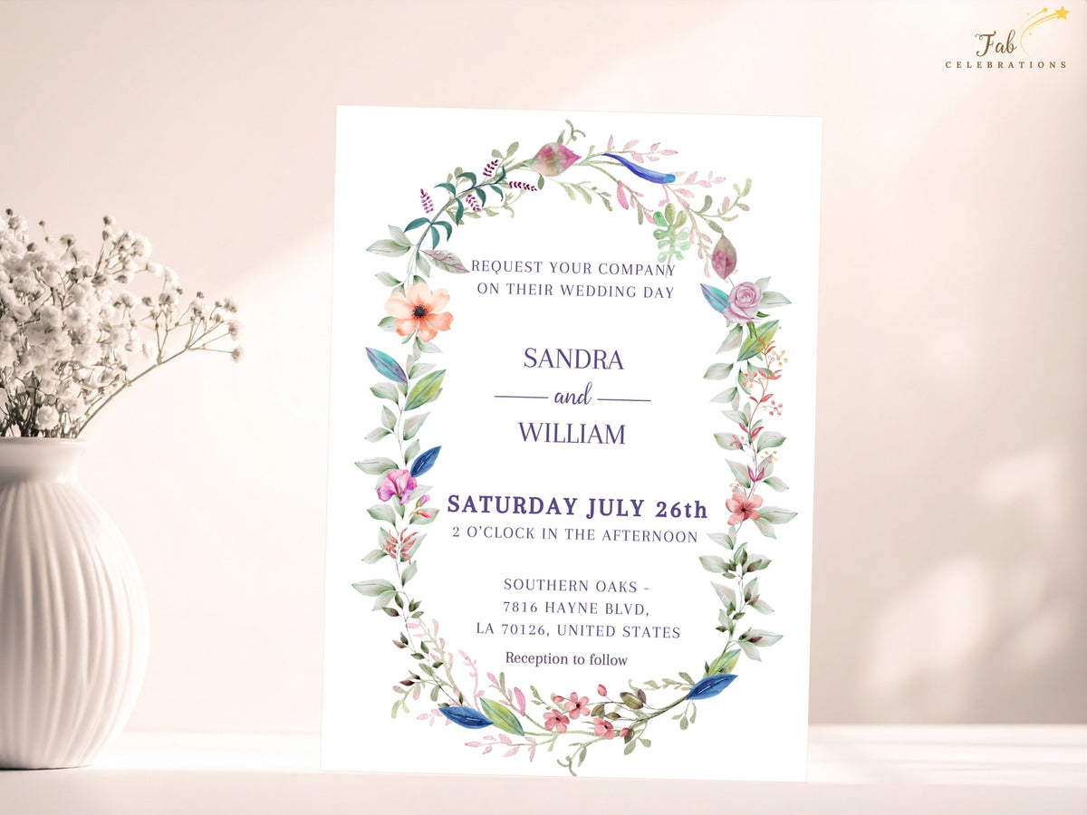 Watercolor wedding invitation featuring an airy floral wreath of pink, peach and blue blossoms with soft green foliage surrounding elegant names and wedding details.