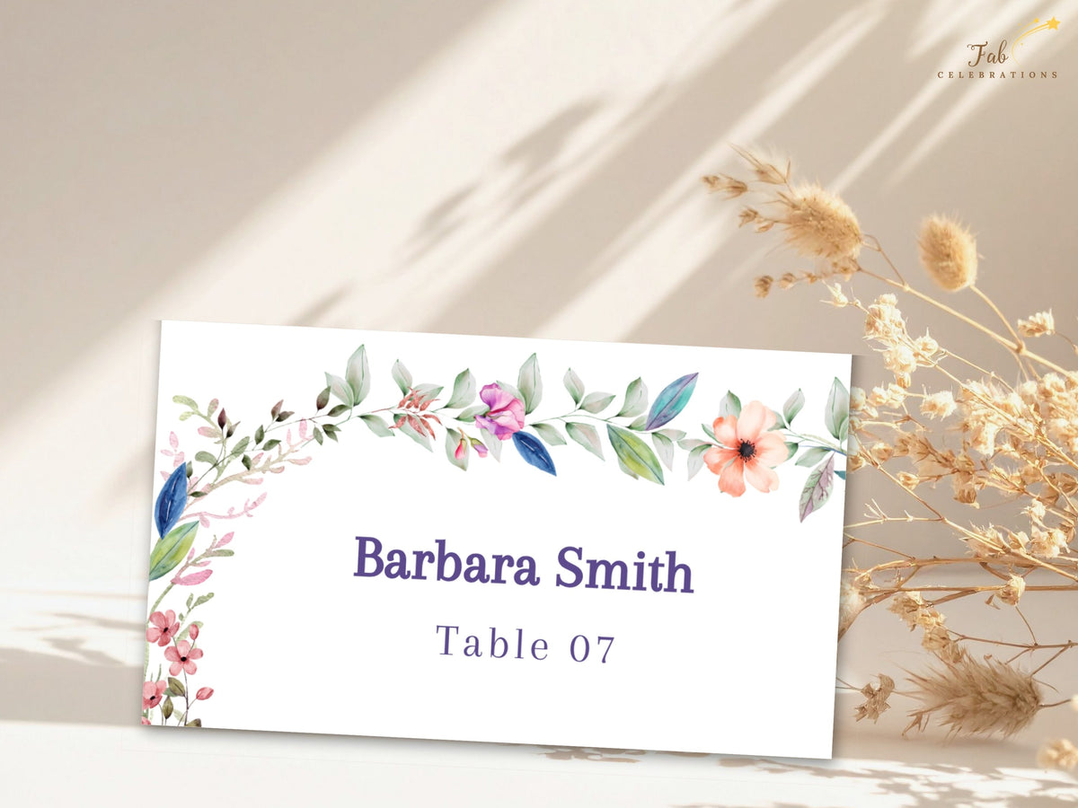 Editable wedding seating card decorated with delicate watercolor-inspired flowers and greenery, featuring a customizable guest name and assigned table number.