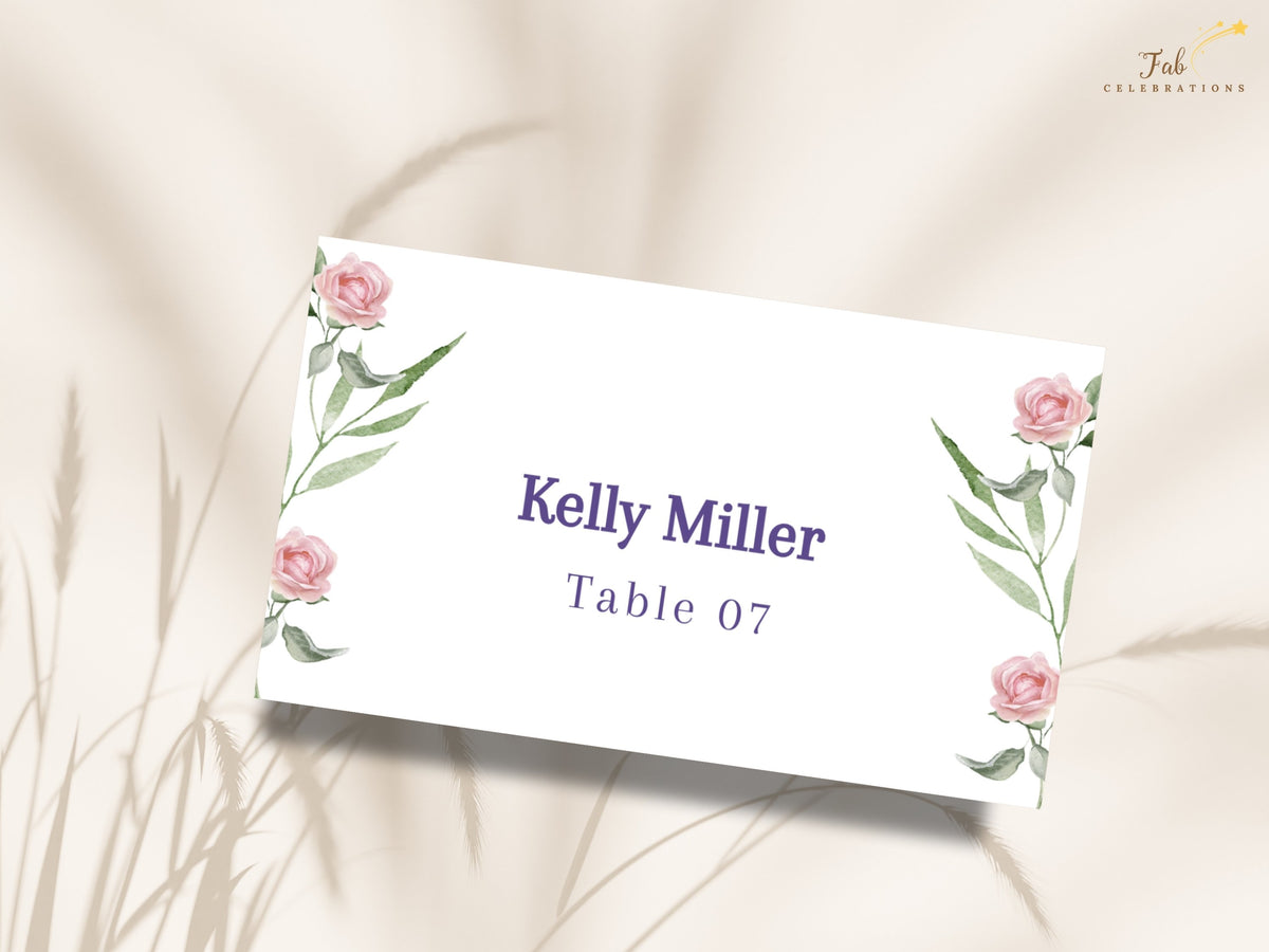 Elegant guest place card featuring watercolor-inspired pink rose corners and slender green leaves, with refined purple typography for the guest name and assigned wedding table.