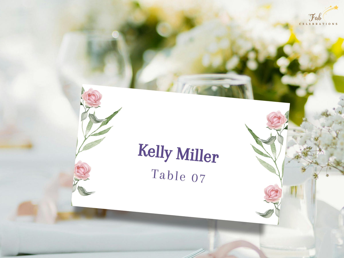 Floral guest name card with watercolor-inspired pink roses and green botanical accents framing personalized purple typography for the guest name and reception table number.