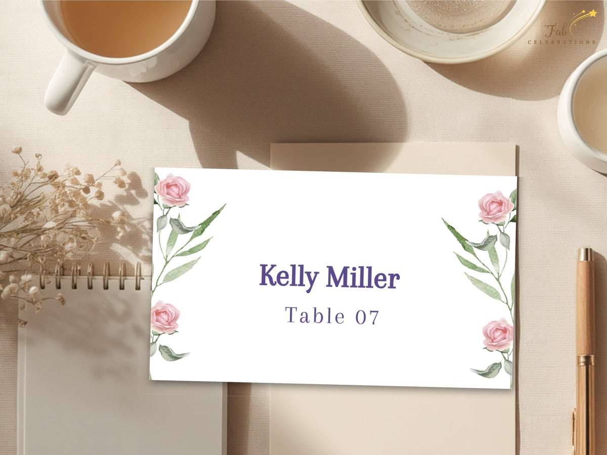 Romantic floral place card featuring watercolor-inspired blush roses and leafy green botanical accents around an elegant guest name and coordinating table number.