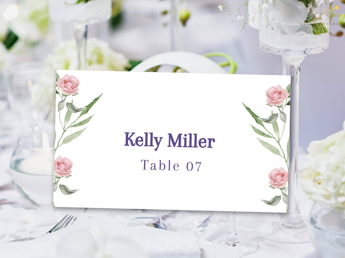 Romantic rose place card featuring watercolor-inspired pink flowers and graceful green leaves around the guest name and table number for a coordinated wedding reception setting.