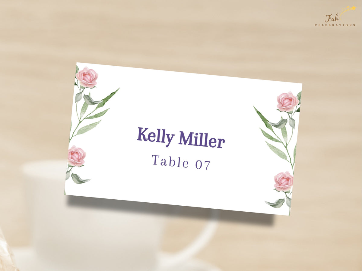 Wedding name card featuring watercolor-inspired blush pink roses and delicate green botanical accents, personalized with the guest name and table number in elegant purple lettering.