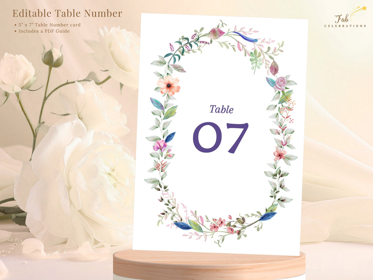 Editable wedding table number shown with descriptive text, featuring a watercolor-inspired floral wreath, elegant typography, and customizable numbering for reception tables.