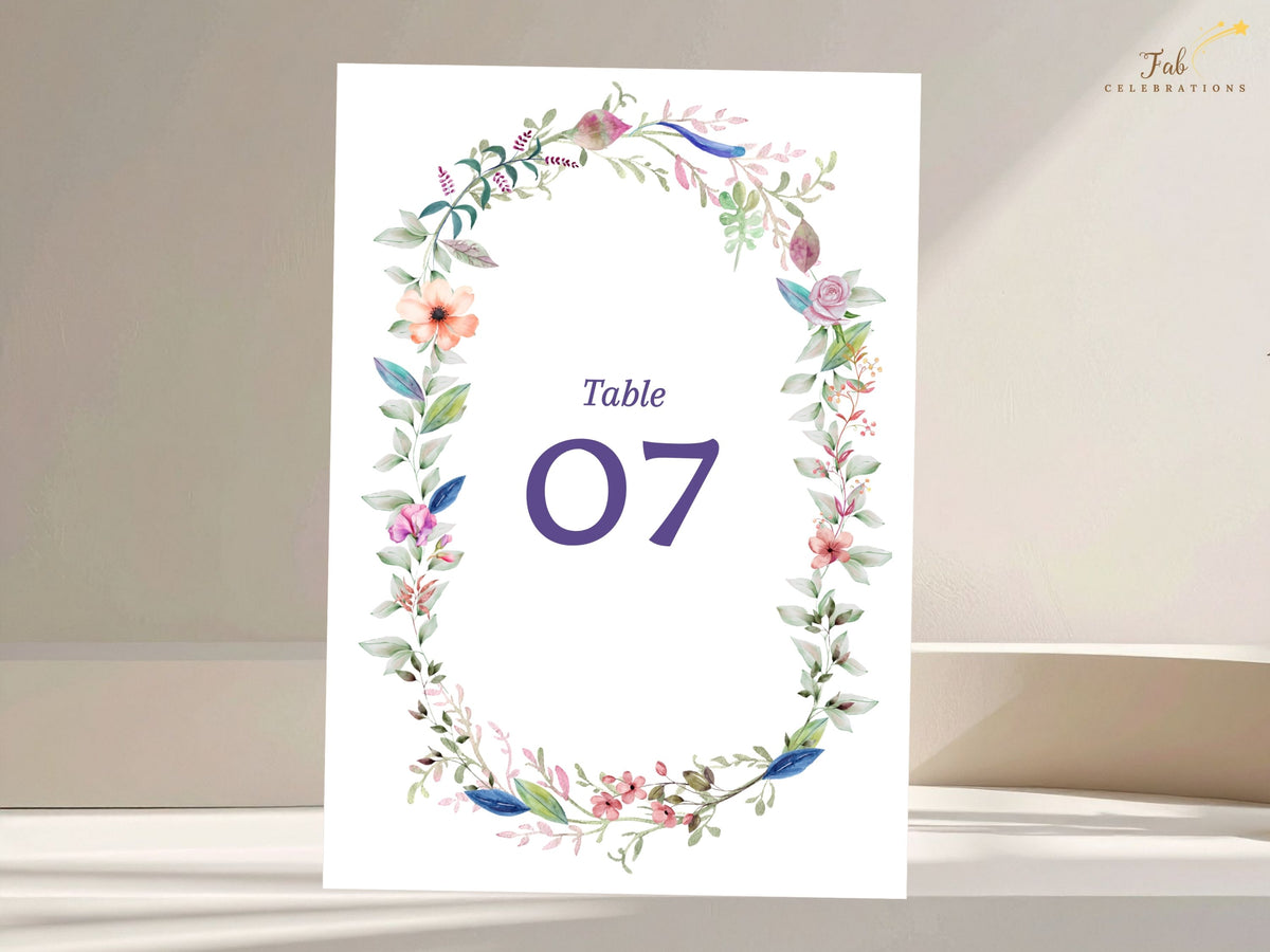 Elegant wedding table number card framed by delicate watercolor-inspired flowers and greenery with customizable numbering for reception seating displays.