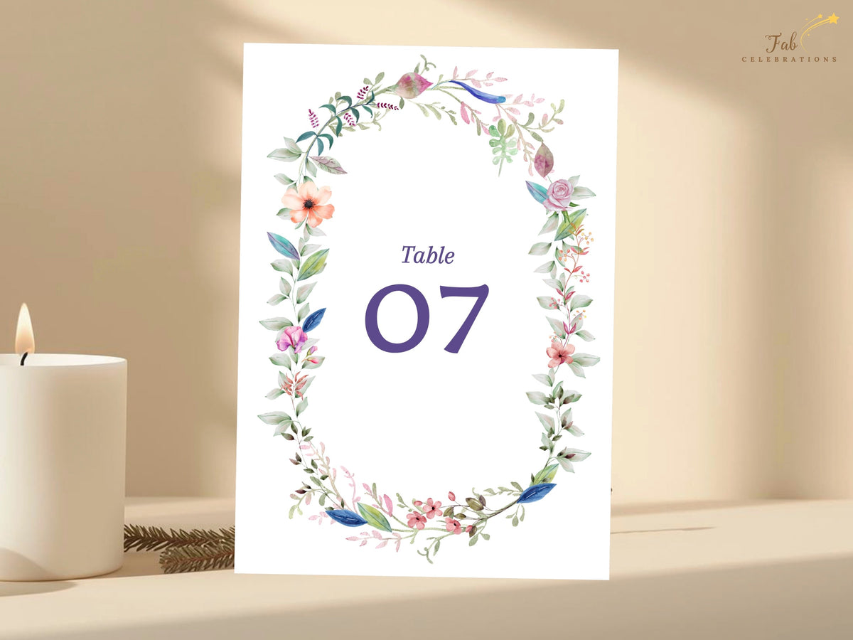Watercolor-inspired wedding reception table sign featuring a delicate floral wreath, soft botanical accents, and prominent customizable table numbering.