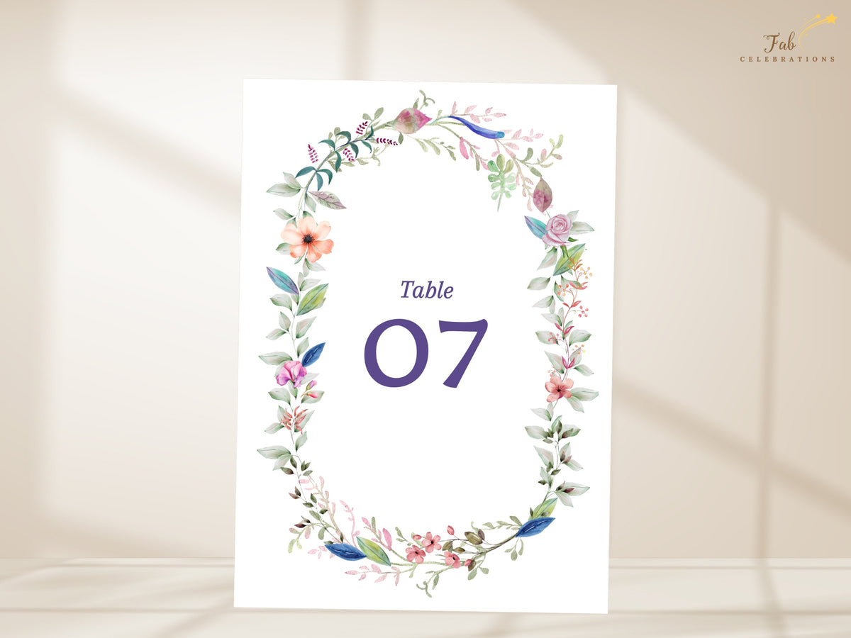Watercolor-inspired wedding table card featuring a delicate wreath of blossoms and greenery surrounding elegant customizable reception table numbering.